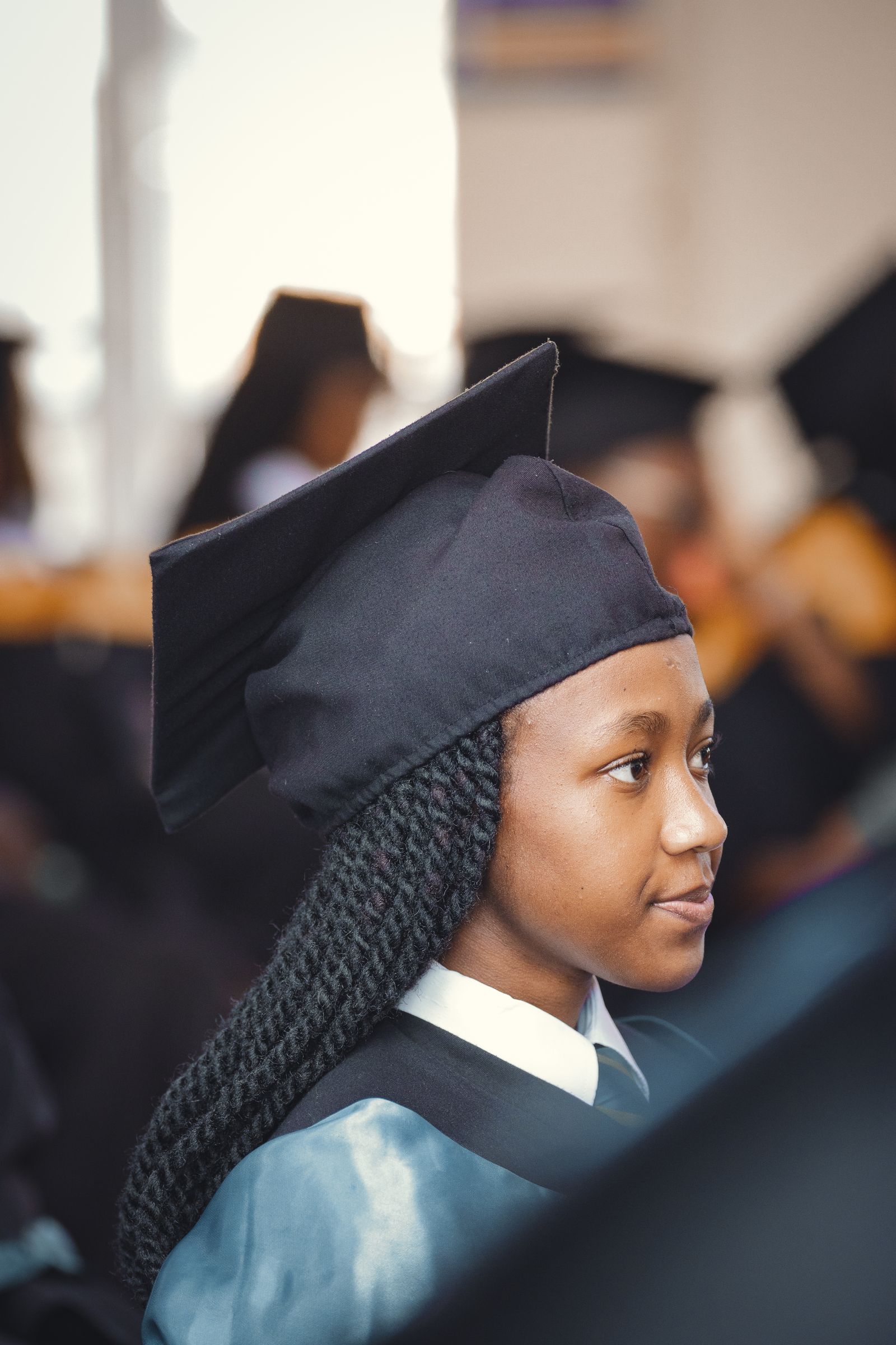 A young graduate in cap and gown at a graduation ceremony.