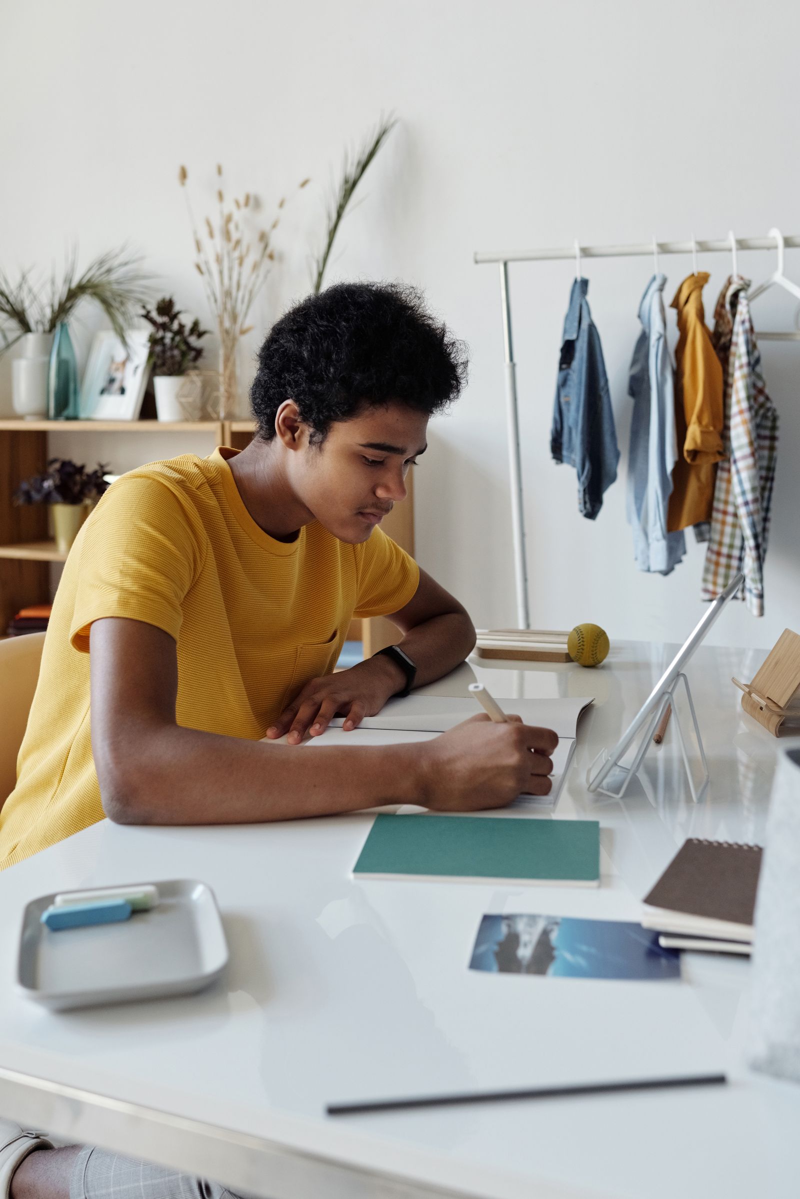 A teenager writing notes at a desk at home.