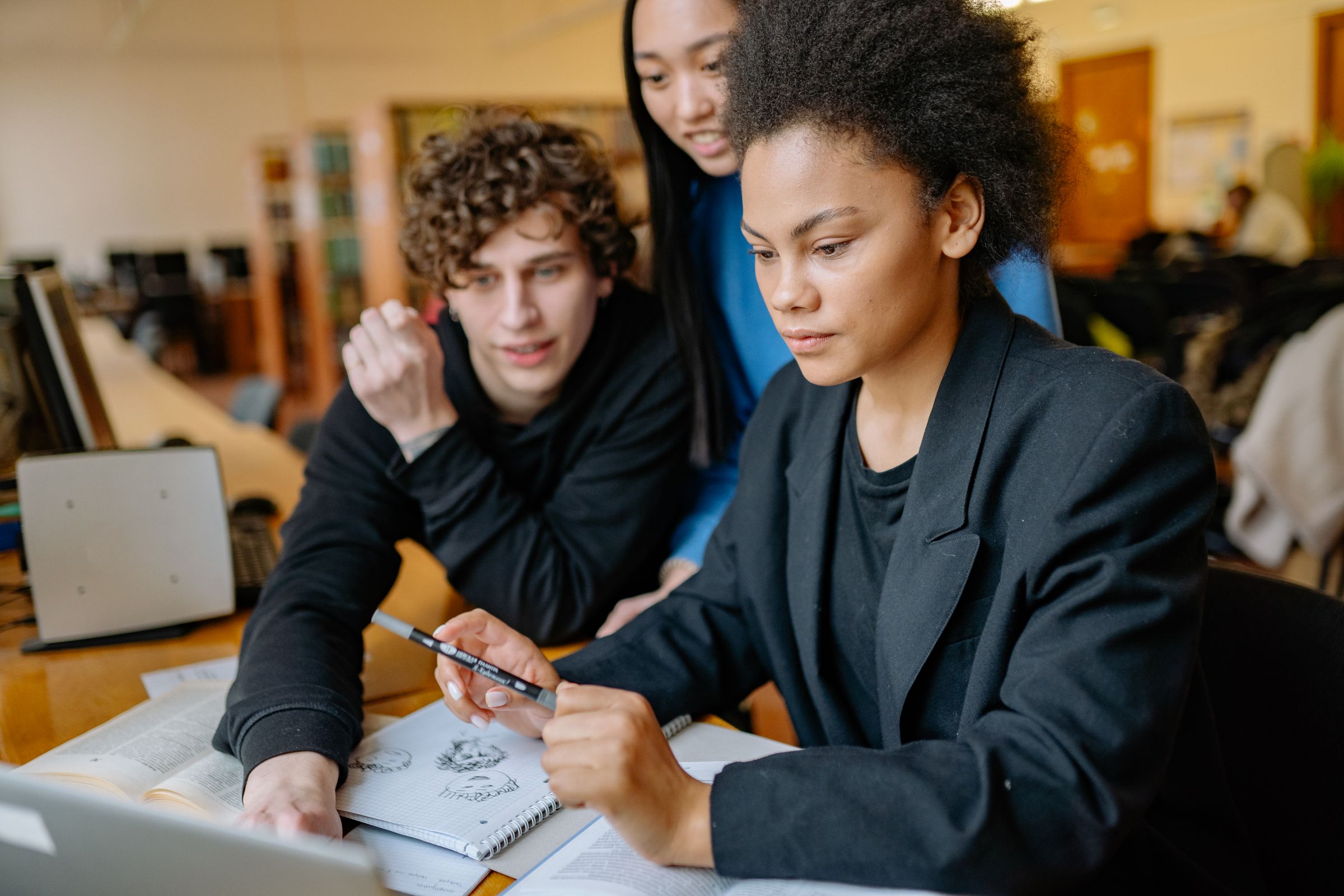 Three students working through a problem together at a library desk.